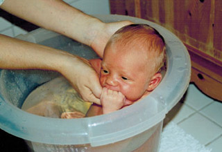 Neugeborenes Baby wird in Badewanne gebadet